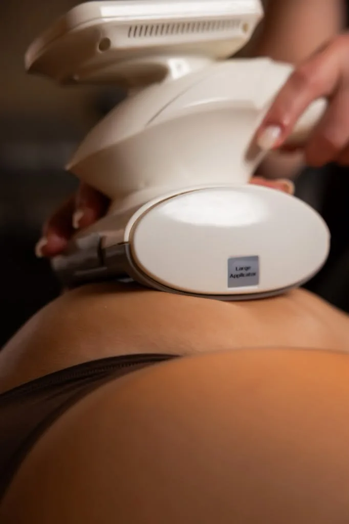 Specialist gliding a body sculpting device over a client's hip