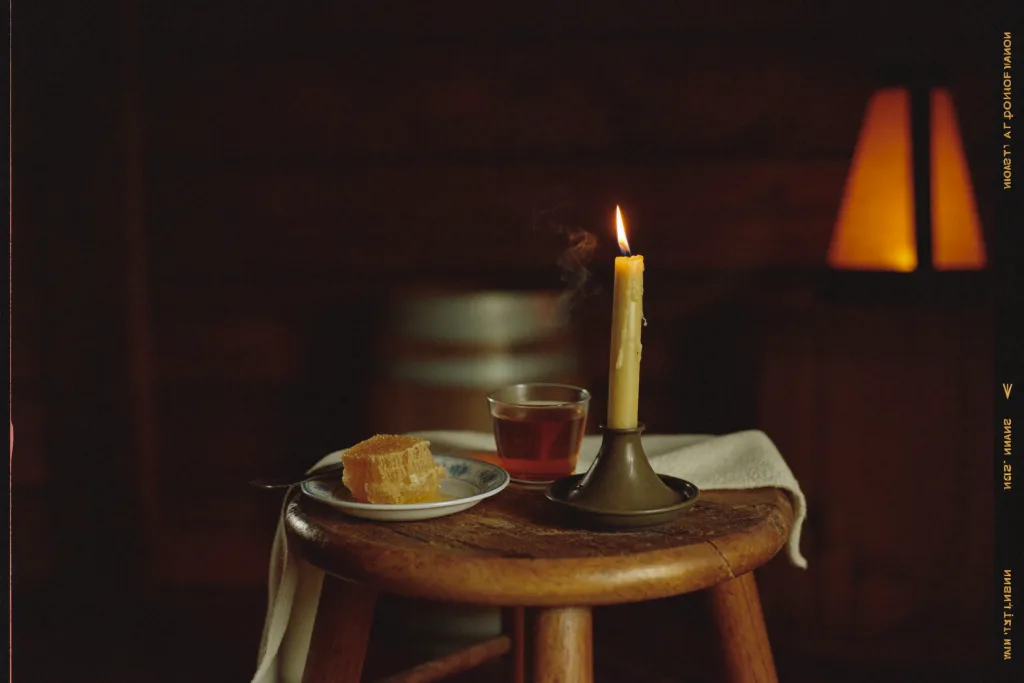 Candle, a glass of tea and honeycomb on a small wooden stool