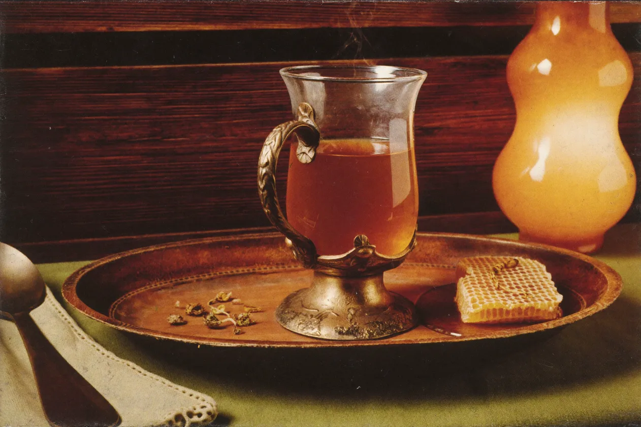 Glass of tea with honeycomb on a copper tray