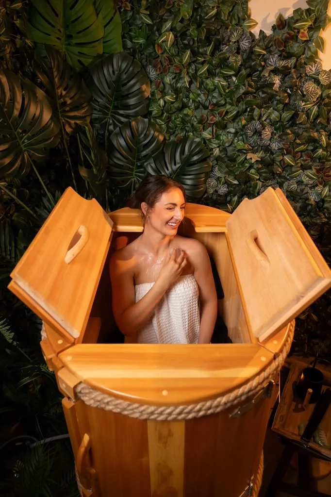 Guest smiling inside an open Siberian cedar barrel at The Body