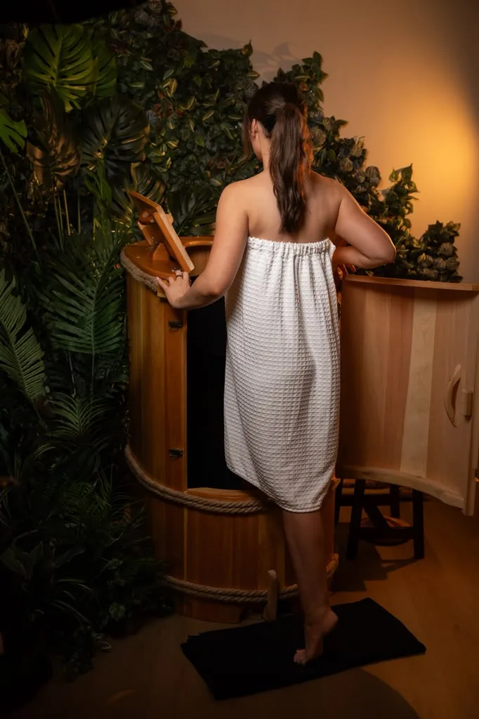 Guest in a towel opening the door of a cedar barrel
