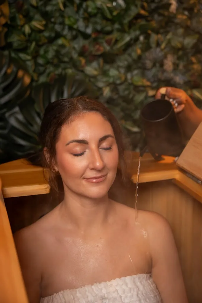Guest relaxing in a cedar barrel during a cedar ritual, eyes closed